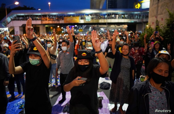 Pro-democracy activists show the three-finger salute during a protest after the constitutional court's ruling on Prime Minister…