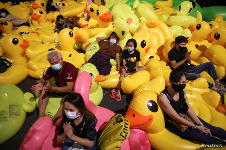 Pro-democracy activists sit on inflatable ducks as they protest after the constitutional court's ruling on Prime Minister…