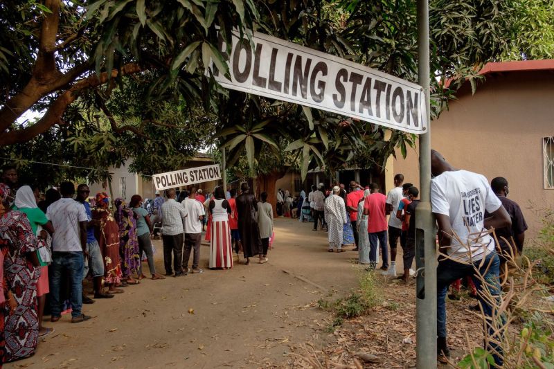 People wait in line ahead of the opening of a voting station in a market in the Kanifing neighborhood in Banjul, Gambia, on Dec. 4, 2021.