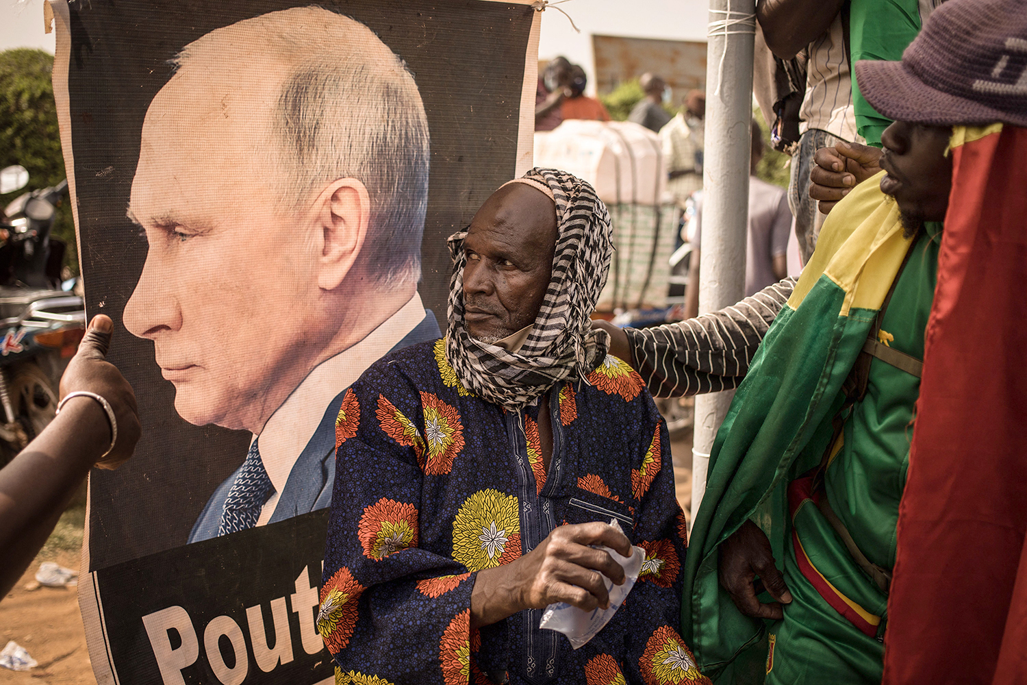 A man sits near a portrait of Russian President Vladimir Putin during a demonstration in Bamako, Mali, on Feb. 19 celebrating France’s announcement that it will withdraw its troops from the country.