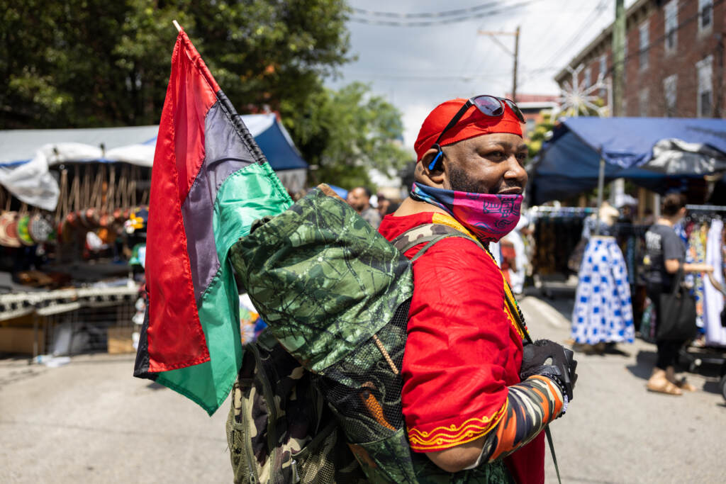 John King walks through the Odunde Festival with his Pan-African, also known as the Afro-American, flag.