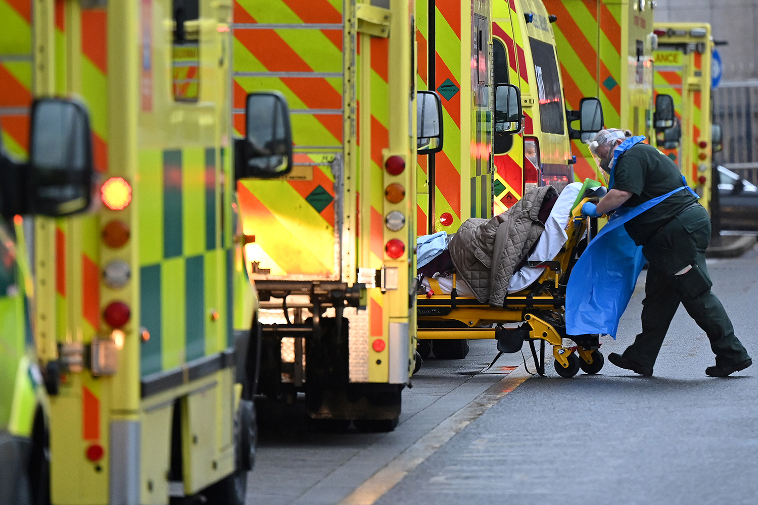 A paramedic pushes a patient near a line of ambulances outside the Royal London Hospital Jan. 5, 2021. JUSTIN TALLIS/AFP via Getty Images